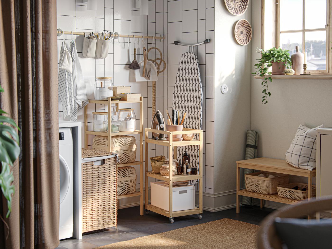 En vaskekrok med oppbevaringsbokser og vaskeromstilbehør på åpne hyller, og et RÅGRUND trillebord, mot en hvit flisvegg.