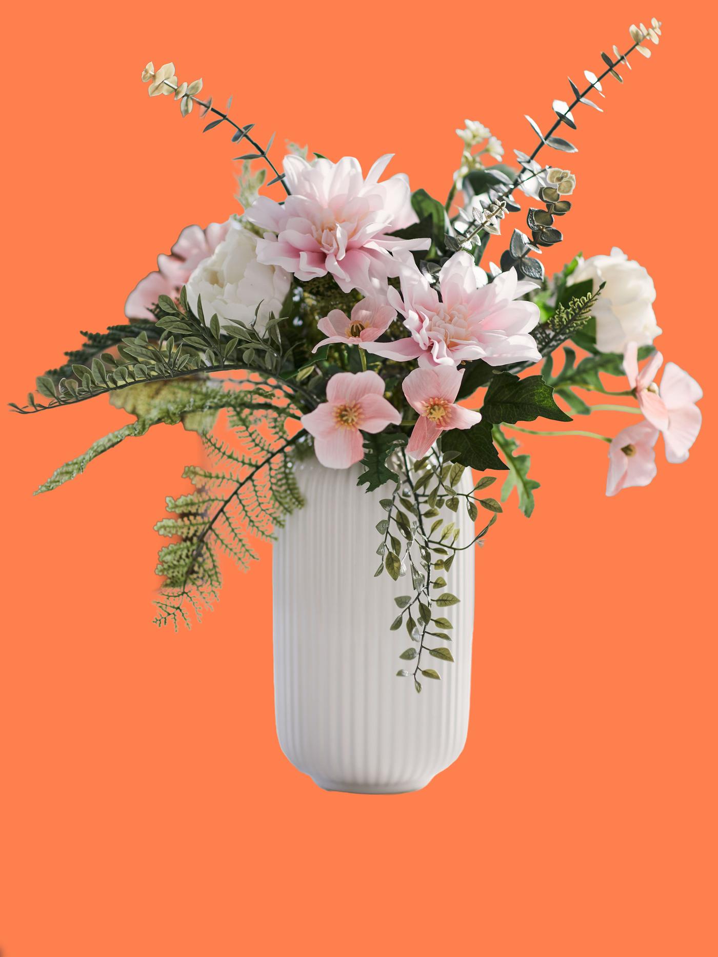 En vit vas med rosa blommor mot en orange bakgrund.