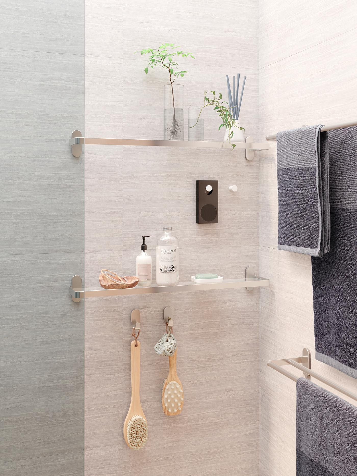 מקלחת אפורה עם מדפי זכוכית ועליהם פריטי דקורציה ומוצרי רחצה, רמקול ENEBY תלוי על ידית לבנה.