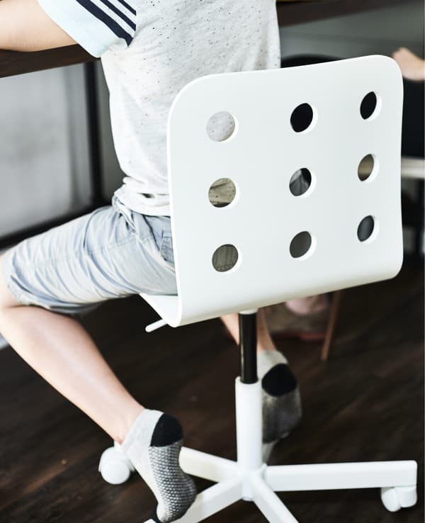 Enfant assis sur une chaise de bureau blanche.
