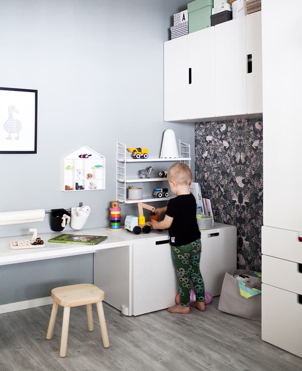 Enfant en train de jouer dans une chambre à coucher aux couleurs neutres, meublée en blanc.