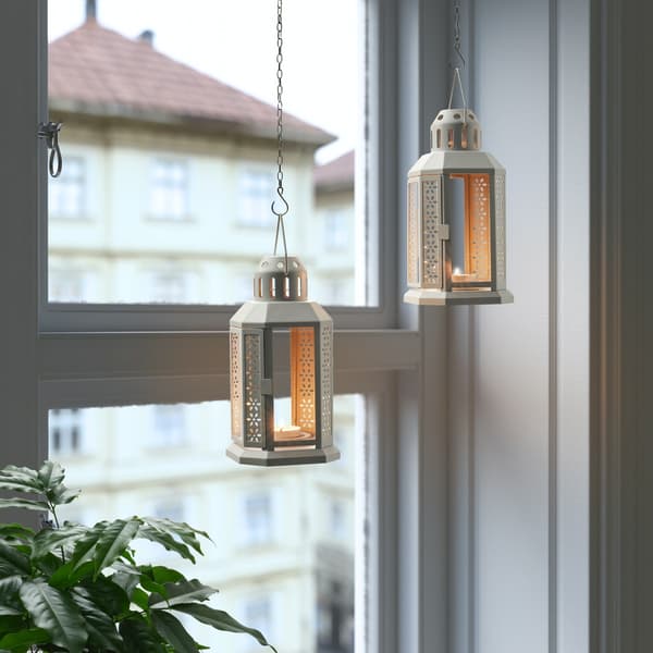 ENRUM lanterns hang in a window, suspended by chains, used as Diwali decorations.  
