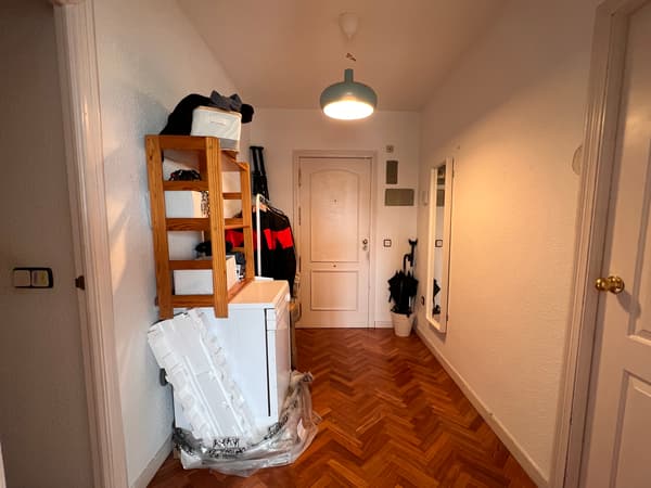 Entrada antes de reformarse con estantería, lavavajillas, lámpara en el techo y accesorios.