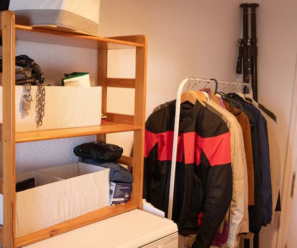 Entrada con perchero, chaquetas y estantería con accesorios.