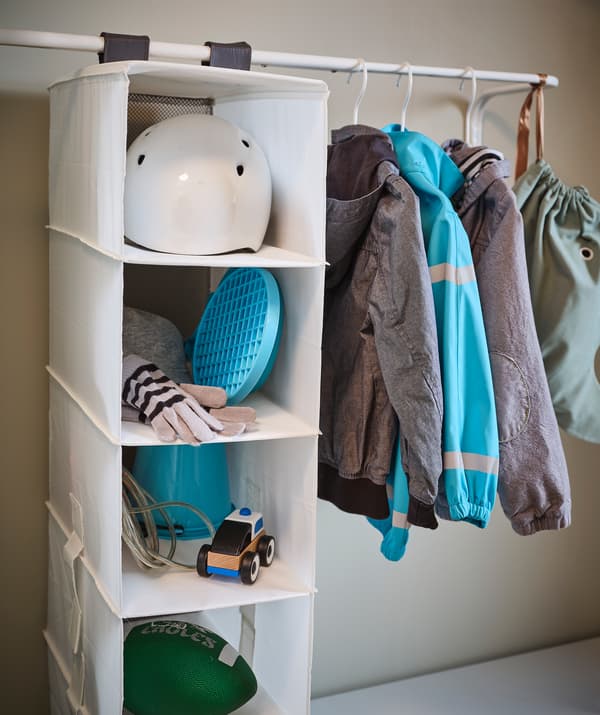 Entrada equipada com varões para roupa MULIG com casacos e um organizador suspenso RASSLA com um capacete de bicicleta, brinquedos e acessórios.