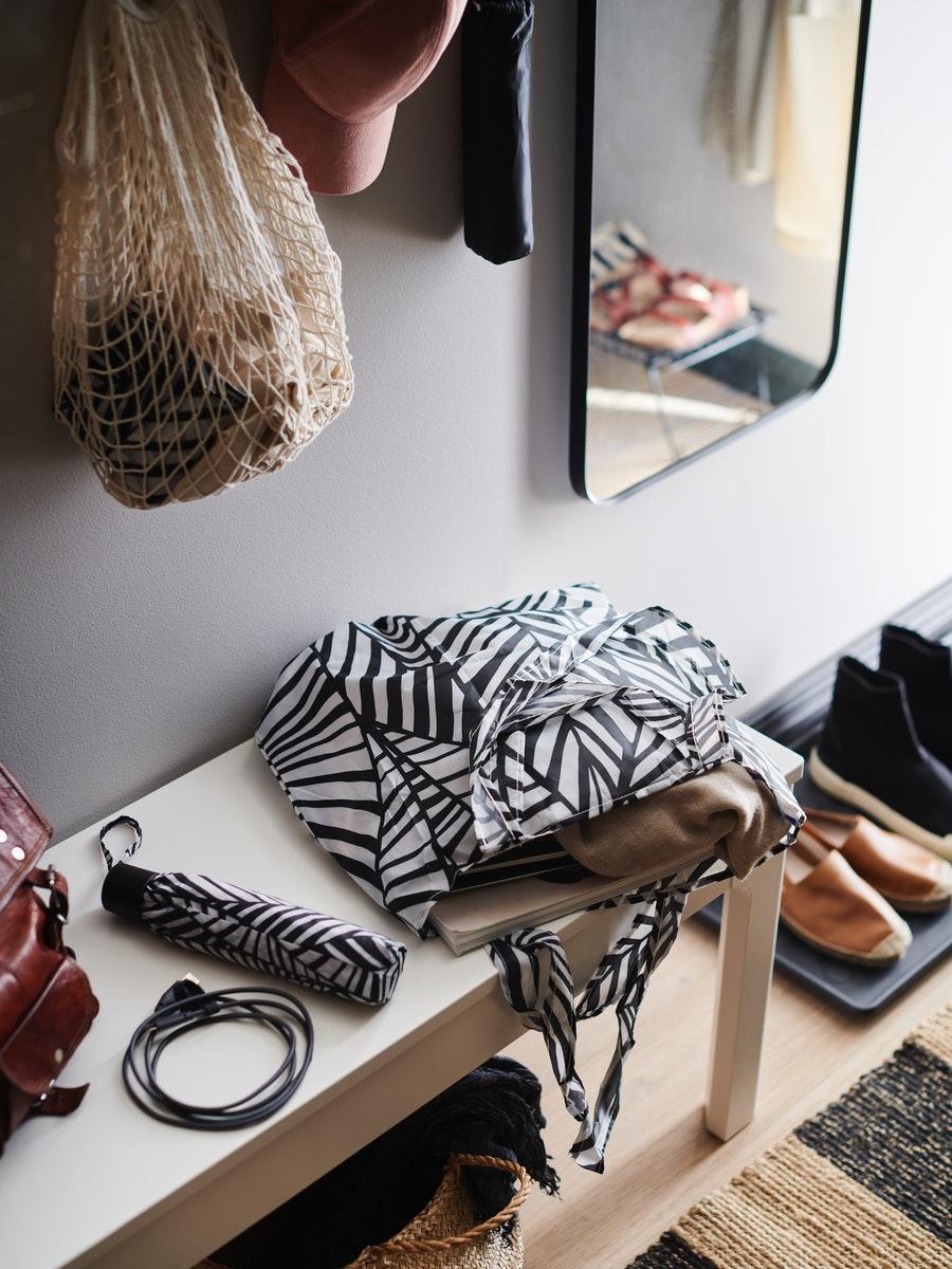 Entryway bench with travel pouches, a hanging mesh produce bag, and shoes stored underneath.