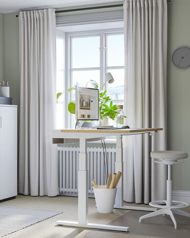 Es ist ein Arbeitsplatz mit einem MITTZON Schreibtisch in Eichenfurnier/Weiß neben einem großen Fenster mit Topfpflanzen zu sehen. 