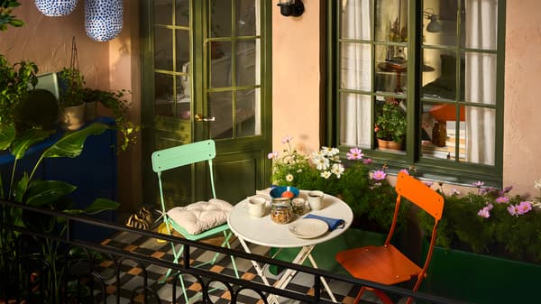 Es ist ein Balkon mit SUNDSÖ Möbeln für draußen in verspielten Farben zu sehen. Außerdem gibt es hier viele Pflanzen und zwei SUNDSÖ Schränke.