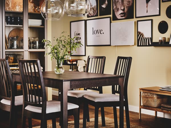 Es ist ein Esszimmer mit einem grauen BILLY Bücherregal, einem EKEDALEN Ausziehtisch, EKEDALEN Stühlen und viel Kunst an den Wänden zu sehen.