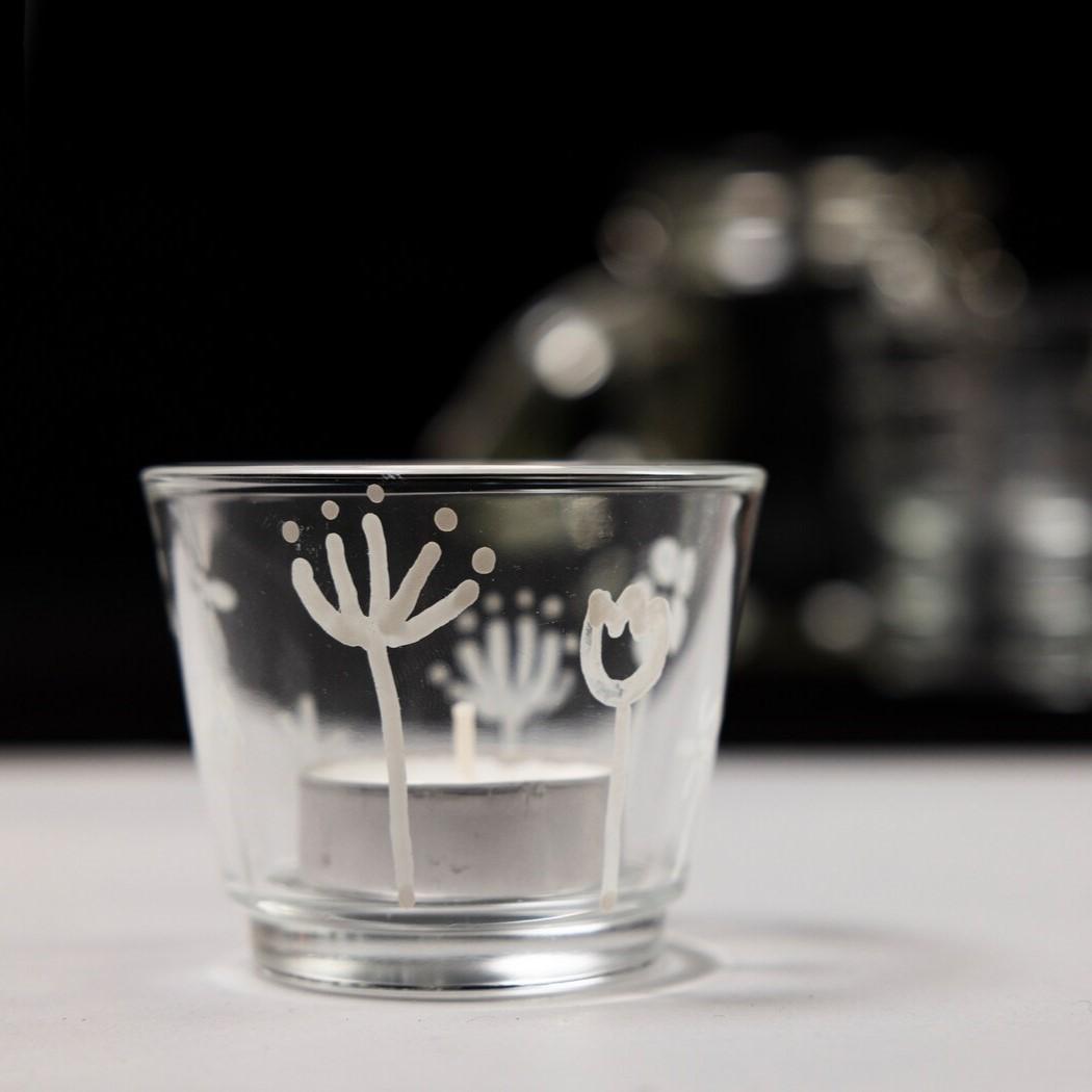 Es ist eine DIY Kerze mit einem weißen Muster auf dem Glas.