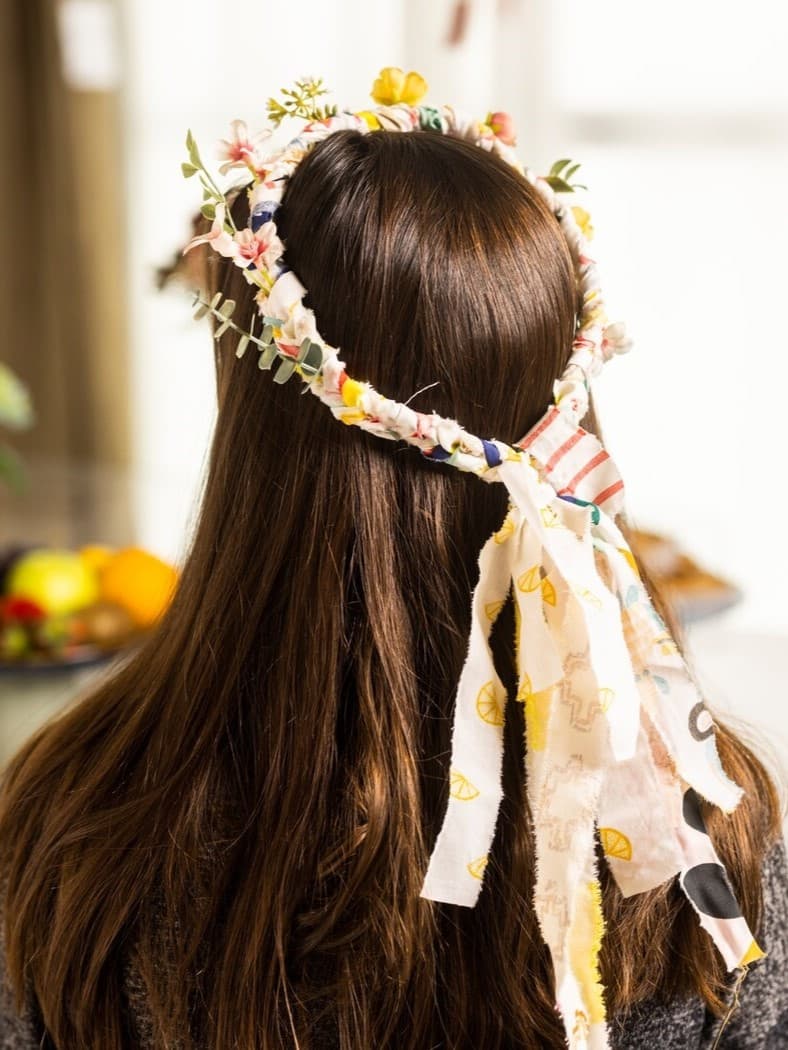 Es ist eine Frau die einen Blumenkranz auf dem Kopf hat mit hellen Farben.