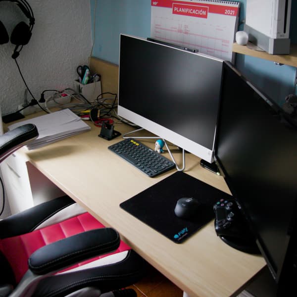 Escritorio de adolescente con dos pantallas de ordenador y una silla de gaming.