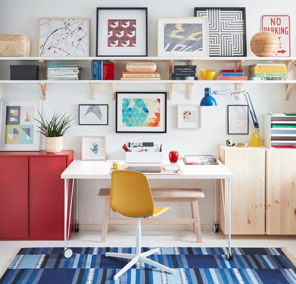 Escritorio junto a silla amarilla y alfombra azul.