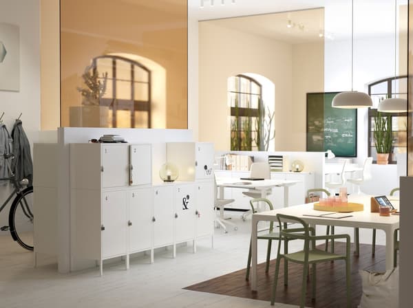 Espace de travail blanc et beige de taille moyenne, avec rangements IKEA HÄLLAN blancs, pratiques et verrouillables.