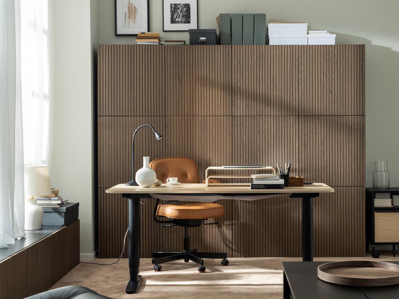 Espace de travail ensoleillé composé d’un bureau assis/debout BEKANT, d’une chaise de bureau ALEFJÄLL et d’une série d’armoires BESTÅ à façade bois.