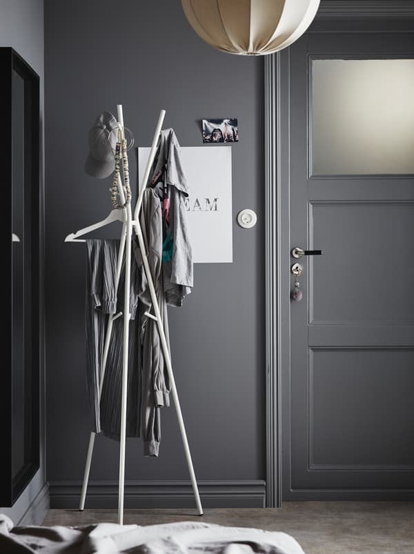 Espace entrée dans une palette de tons gris. Près de la porte d’entrée, un portemanteau EKRAR où sont suspendus divers vêtements.