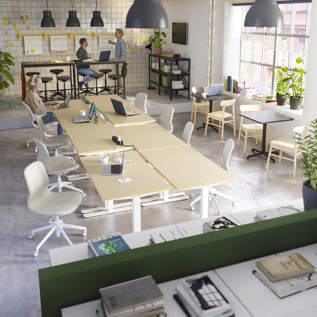 Espacio de trabajo de oficina abierta, con varias sillas SKARSTA. Al fondo se ve un8 par de personas conversando.