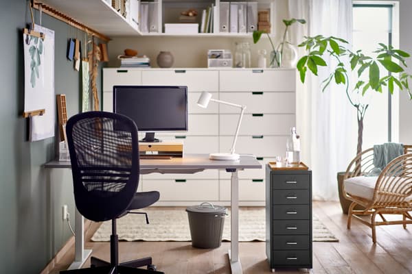 Espacio de trabajo en casa donde hay un escritorio, una silla FLINTAN negra y una pantalla de computador.