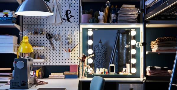 Espacio de trabajo en un dormitorio con un escritorio, máquina de coser, tocador y tablero perforado IKEA SKÅDIS.