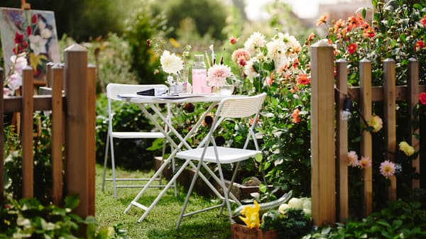 Espacio exterior con juego de terraza blanco FEJAN junto flores.