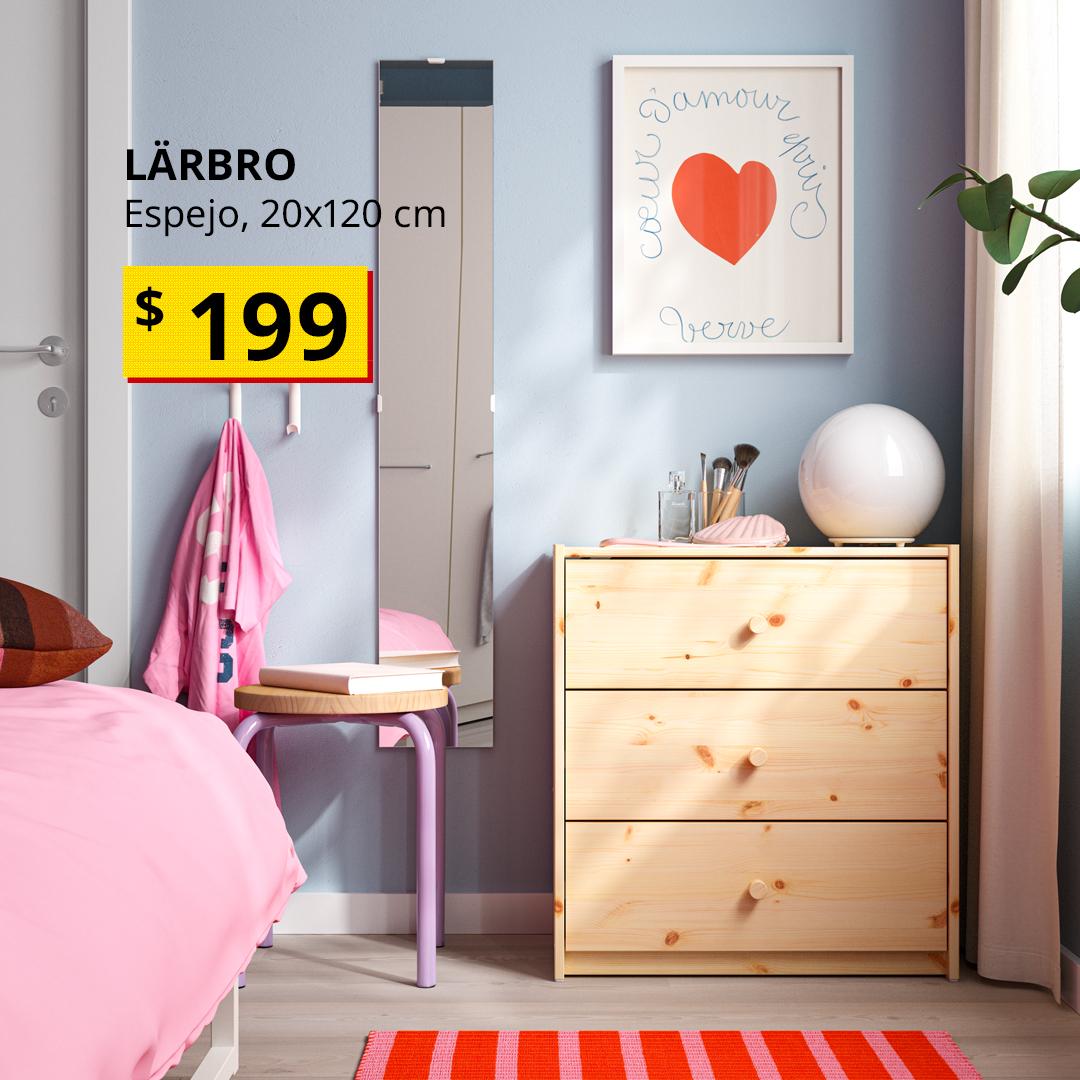 Espejo LÄRBRO colocado en la pared de un dormitorio, junto a una cómoda de madera y una cama con ropa de cama rosa.