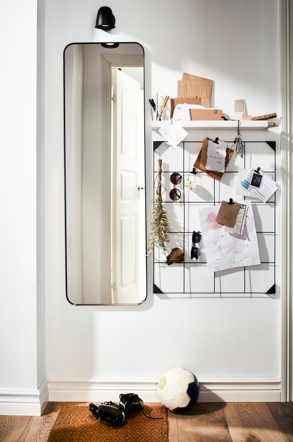 Espejo largo junto a un tablero de pared con notas, cartas y decorativos.