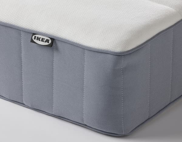 Esquina de un colchón de muelles embolsados IKEA VESTERÖY de color blanco por arriba y gris oscuro en los laterales.