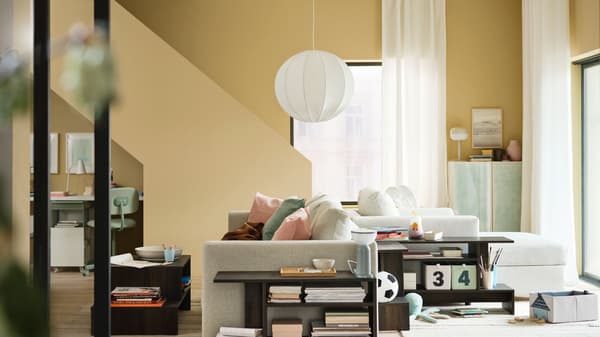 Estancia del hogar con dos sofás, lámparas, mesas con almacenaje, escritorio, ventana, cortinas y elementos de decoración.
