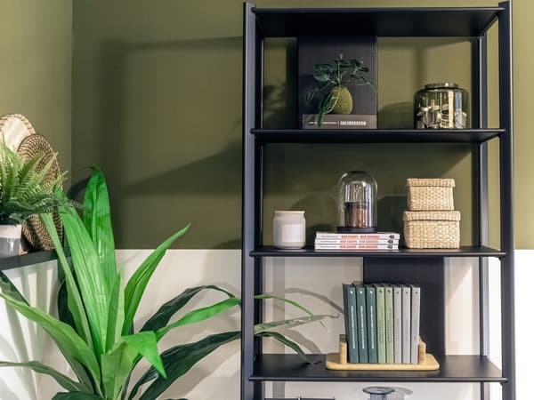 Estante aberta JÄTTESTA em preto com objetos decorativos e plantas ao lado.