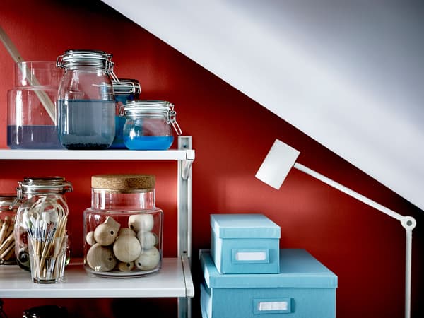 Estante con material para facer manualidades nunha zona con teito inclinado.