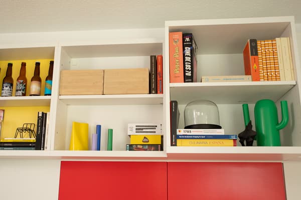 Estantería blanca con cajas, libros y objetos.