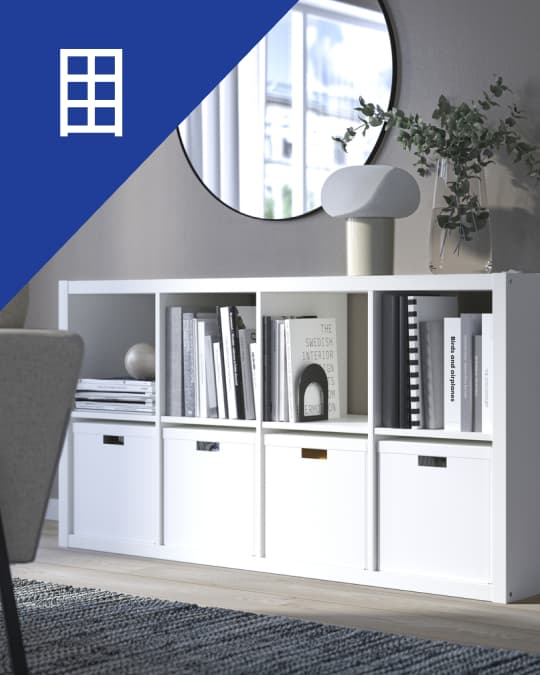 Estantería blanca con compartimentos y cajas de almacenamiento.