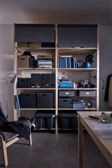 Estores opacos TUPPLUR grises fijados a la estantería. Bájalos cuando no quieras que se vean las cosas.