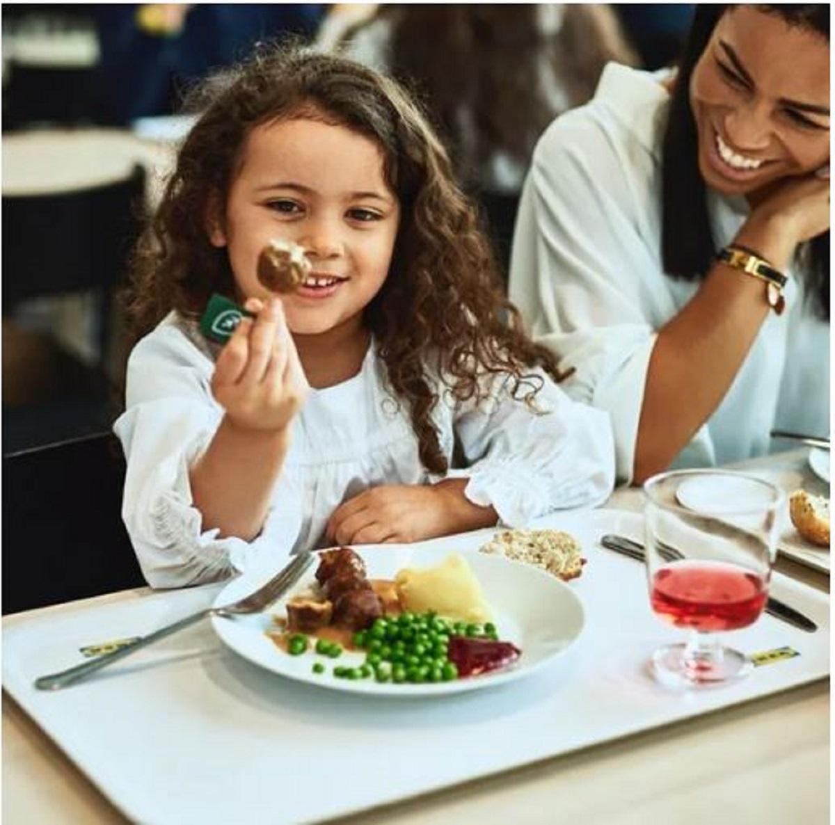 Et barn og en kvinne sitter smilende i IKEA Restauranten med kjøttbollemiddag.