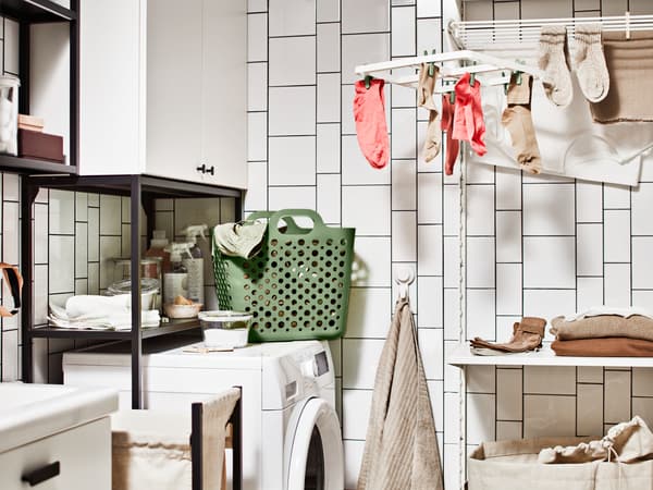 Et klesvaskhjørne med vaskemaskin, en oppbevaringskombinasjon til skittentøy og et SLIBB tørkestativ med hengende sokker.