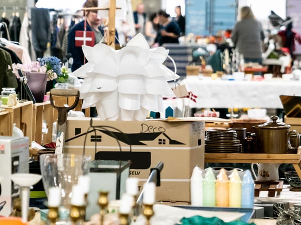 Et loppemarked er fyldt op med ting og en hvid lampe hænger op i midten. 