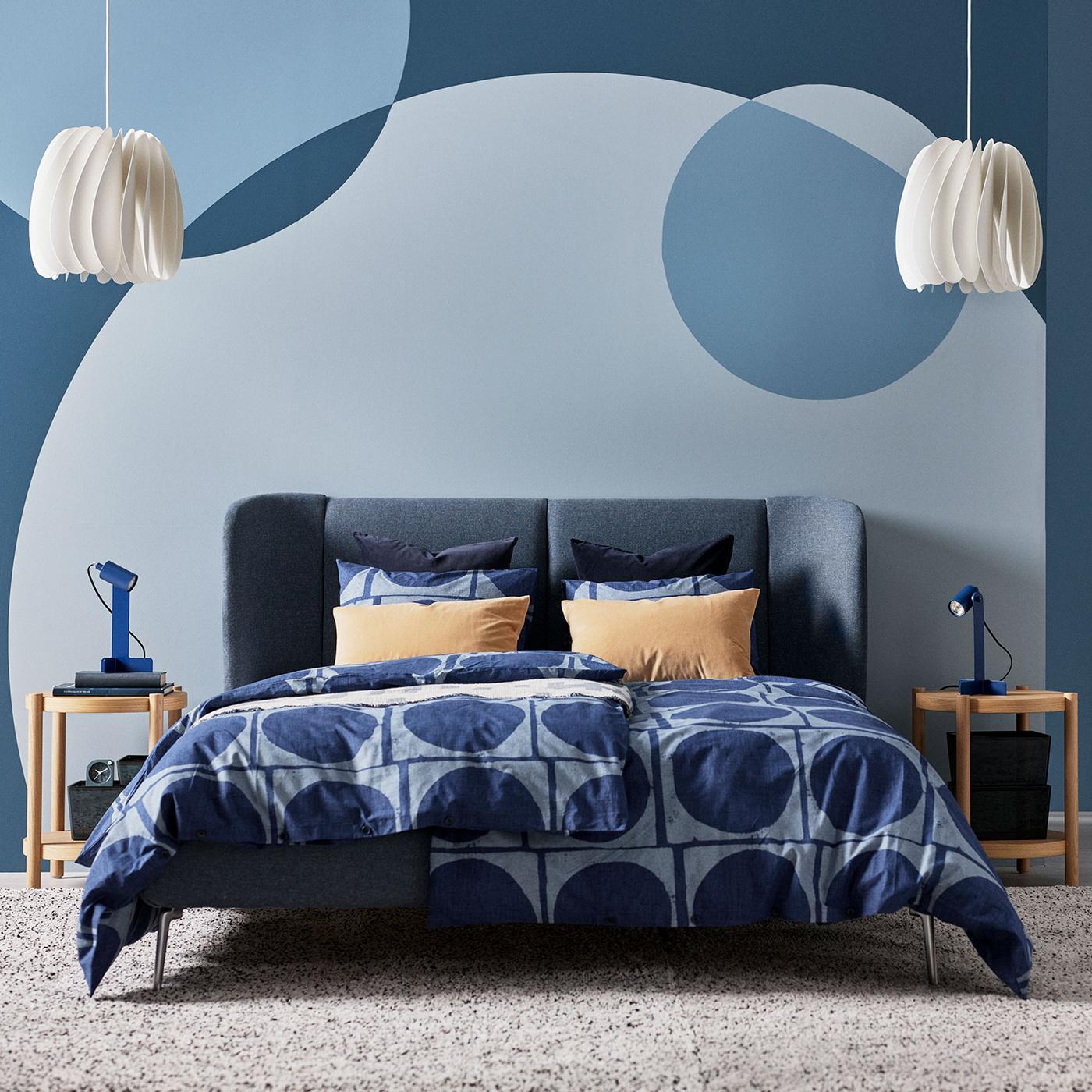 Et lyst soveværelse med en luftrenser på hvide kommoder ved siden af en seng.