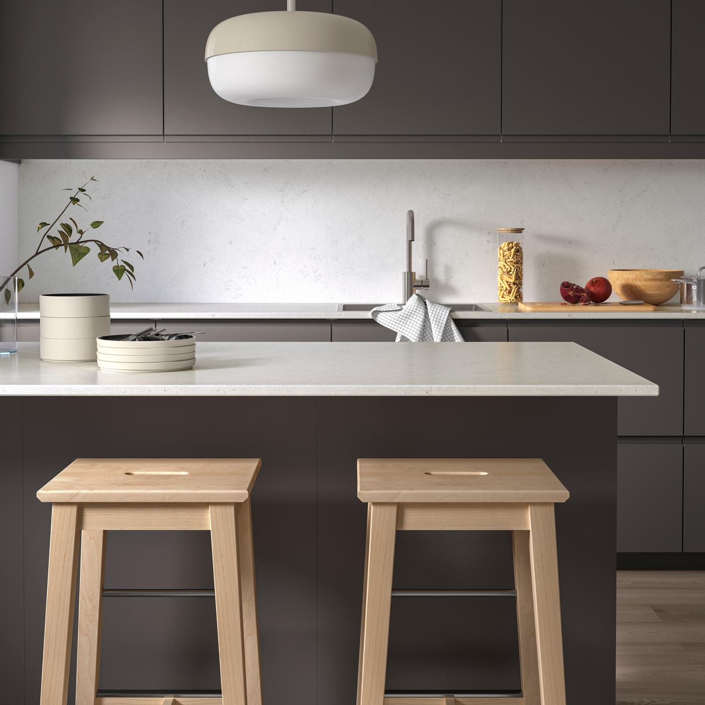 Et mørk grått VOXTORP kjøkken med LOCKEBO benkeplate i glasskompositt.