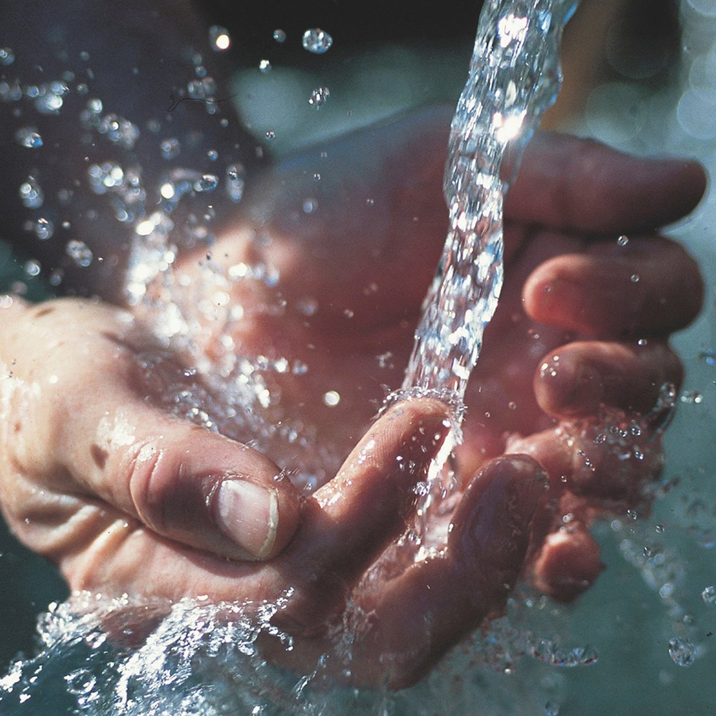 Et par hænder former en skål uner en stråle af vand.
