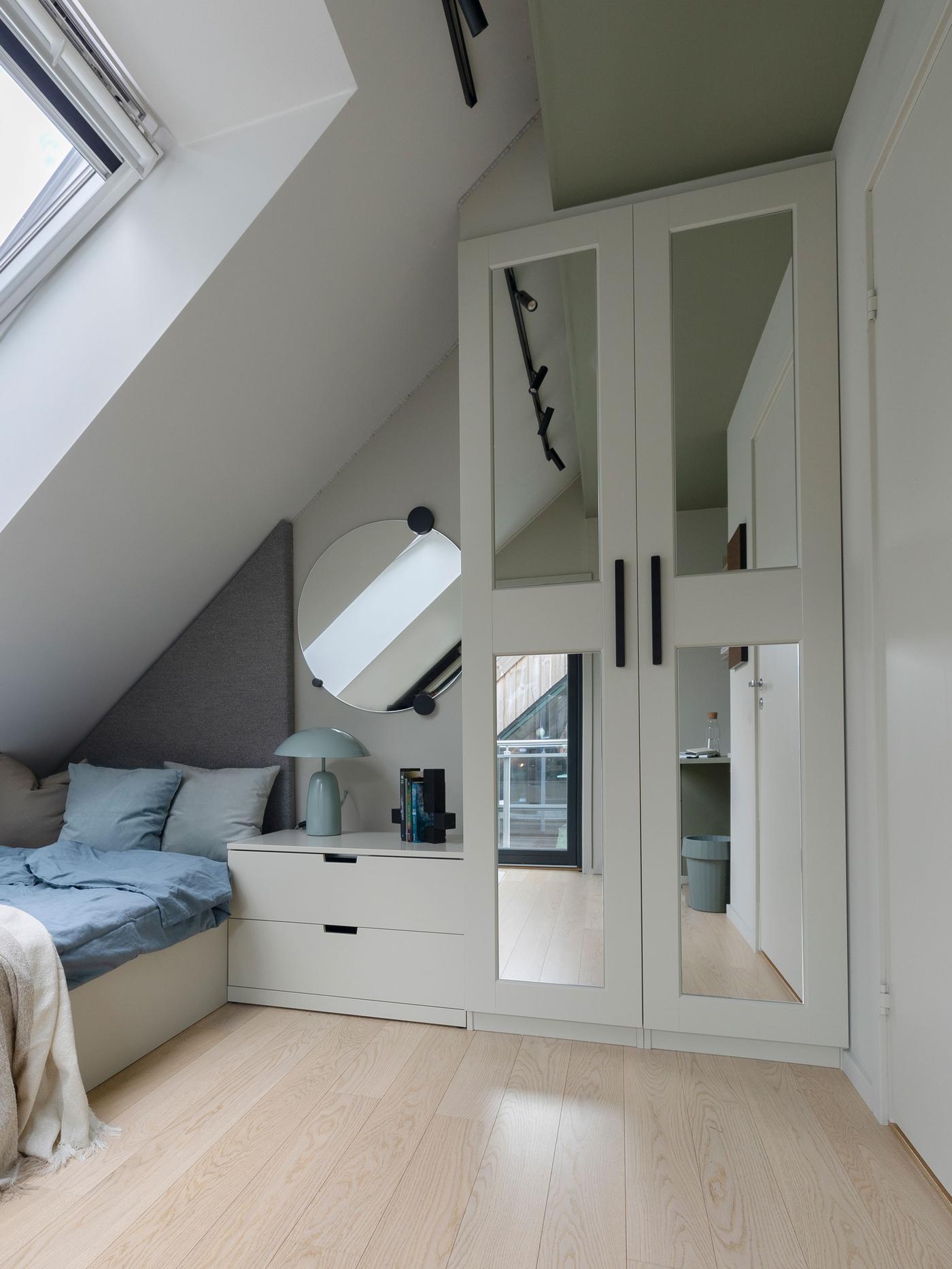 Et PAX GRMO garderobeskap i et soverom med skråta og en seng under vinduet.