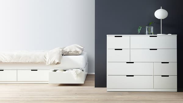 Et sengebord, en dobbeltseng med opbevaring og en kommode fra NORDLI serien - alle i hvid.