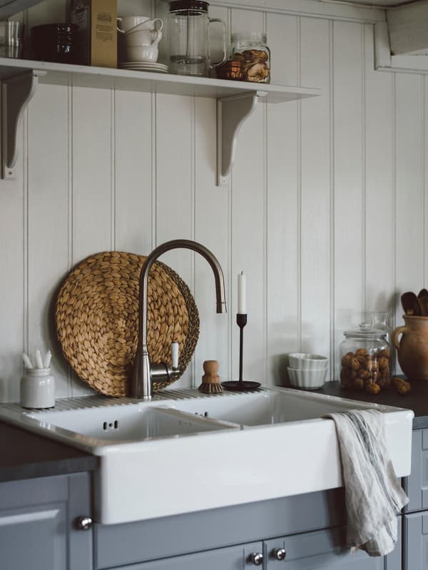 Et sommerhuskøkken i traditionel stil med grå BODBYN fronter og en hvis keramisk vask.