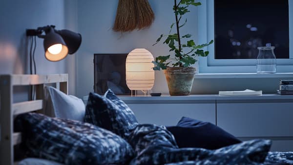 Et soveværelse med to natlamper over en dobbeltseng og en papirlampe på kommoder op ad væggen ved siden af sengen.