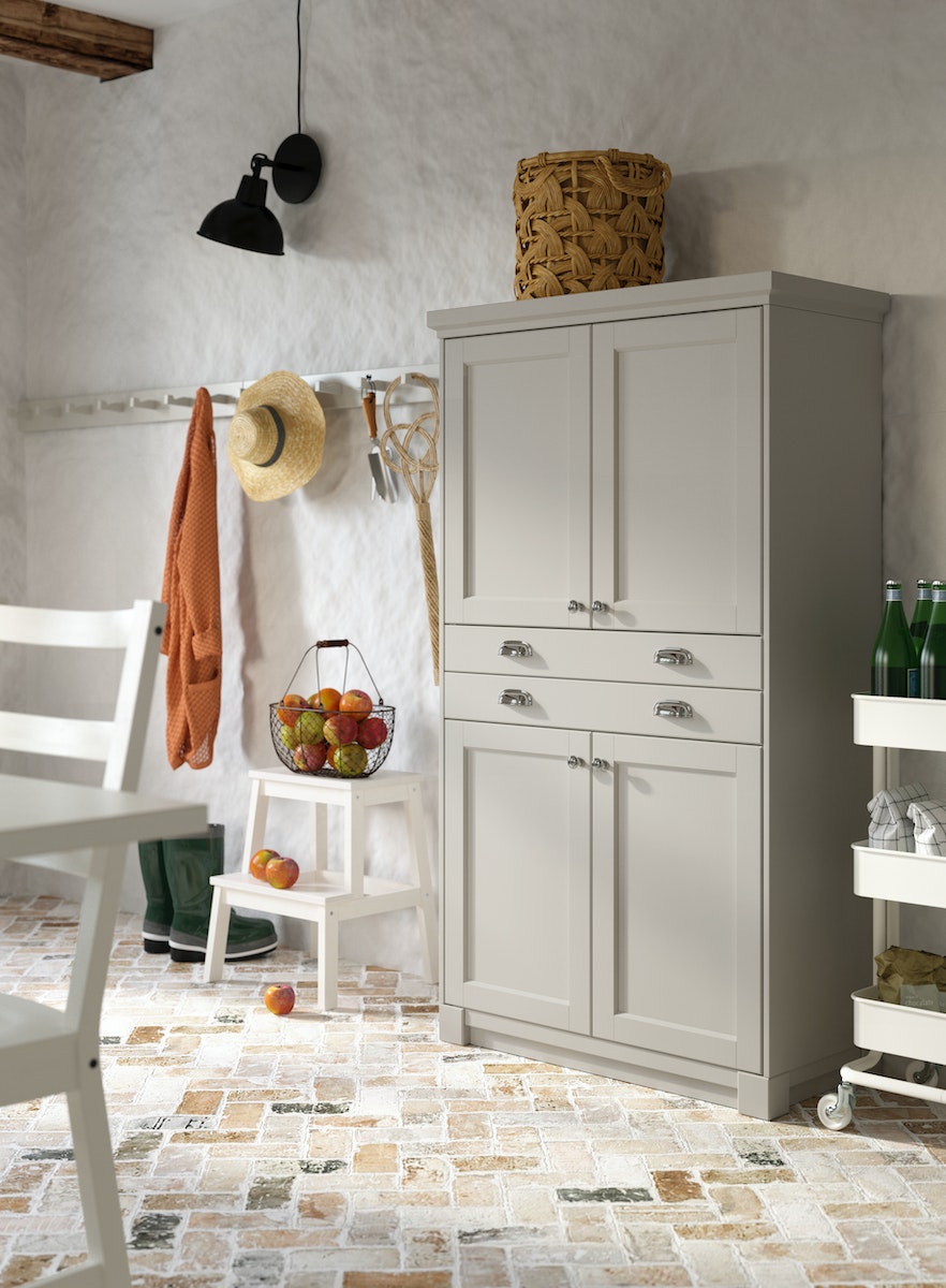 Et vitrineskab sammensat af METOD skabe og grå LERHYTTAN fronter op af en væg med fritlagte bjælker.