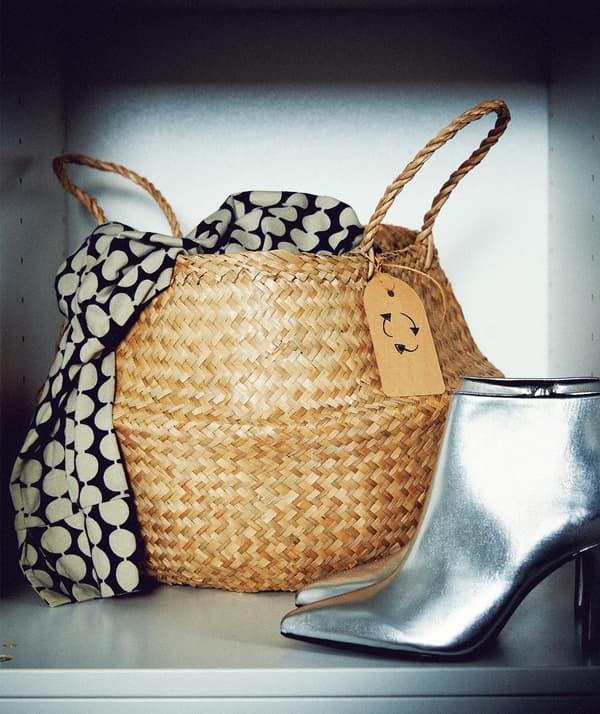 Étagère de garde-robe avec un panier et une étiquette de recyclage dessus dont s’échappe une partie de foulard; une paire de bottes argentée se trouve à côté.