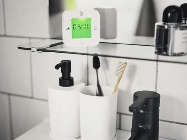 Etagère de salle de bain portant divers produits dont un réveil.