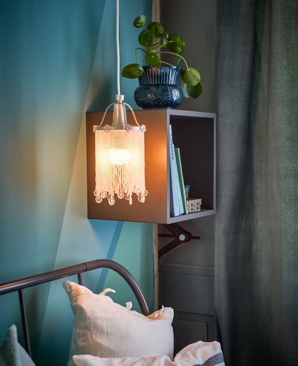 Étagère et lampe à perles près du lit.
