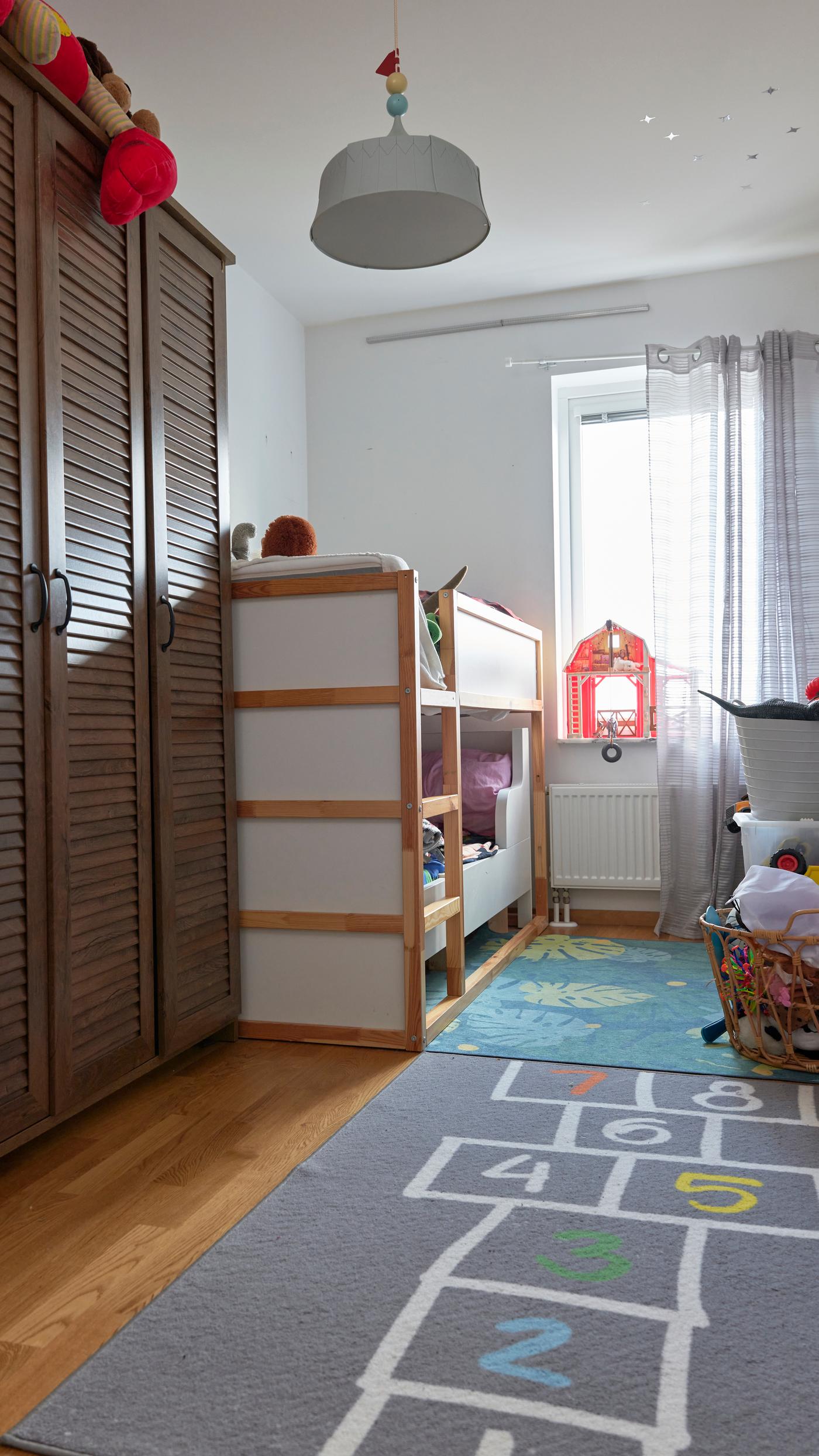 Ett delat barnrum före en rumsmakeover. Längst in i rummet finns en våningssäng och på golvet ligger en matta med en hopphage på.