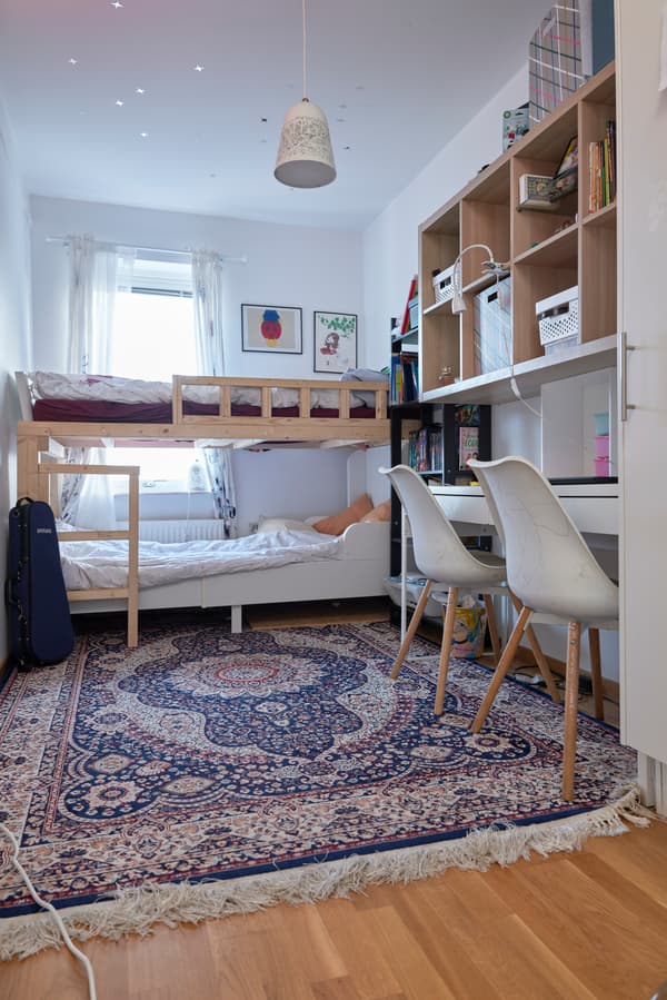 Ett delat barnrum före en rumsmakeover. Längst in i rummet finns en våningssäng och på golvet ligger en orientalisk matta.