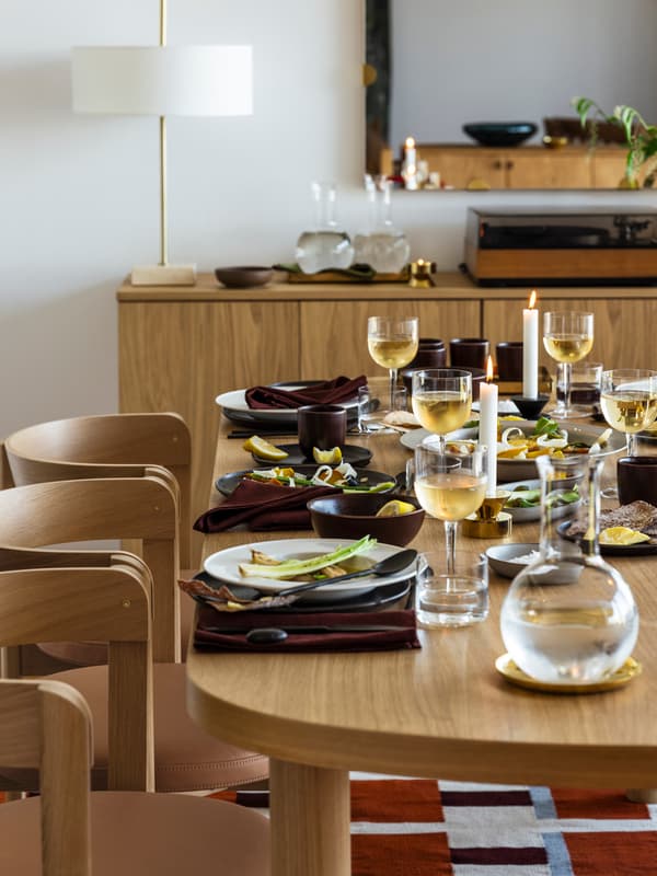 Ett elegant dukat matbord med vita tallrikar, vinglas och tända ljus.